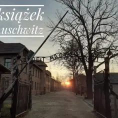 Brama obozu Auschwitz-Birkenau. W tle wschód słońca i budynki. Tekst: "7 książek o Auschwitz". Każda literatka przypomina o historii.