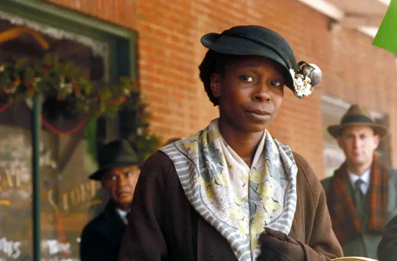 Whoopi Goldberg w kapeluszu i apaszce, jak z jej filmów i seriali. W tle mężczyźni w kapeluszach.